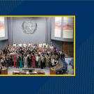 large group of people in a large room with the United Nations symbol above them on the back wall